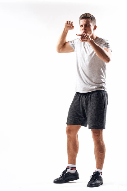 Hafif bir geçmişi olan atletik bir adam tam boy ve koşu şortu spor ayakkabısı tişörtü giyiyor. - Fotoğraf, Görsel