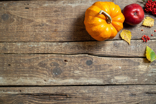 Φθινοπωρινή σύνθεση για την Ημέρα Ευχαριστιών. Κολοκύθα, φρούτα μήλα, φθινοπωρινά φύλλα σε ρουστίκ ξύλινο τραπέζι. Φθινοπωρινή διακόσμηση. Φθινόπωρο φόντο. Πάνω όψη, αντιγραφή χώρου - Φωτογραφία, εικόνα