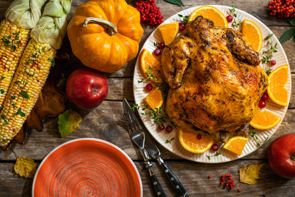 Syksyn juhlava kiitospäivän sävellys. Paistettua kanaa tai kalkkunaa sitrushedelmillä ja mausteilla kiitospäivän illalliseksi puupöydällä. Kiitospäivän pöytäasetukset - Valokuva, kuva