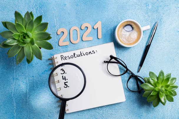 Oud en Nieuw Resolutie 2021 op het bureau. 2021 goals met notitieboekje, koffiebeker en bril op houten ondergrond. Doelstelling, plan, strategie, actie, idee concept. Kopieerruimte - Foto, afbeelding