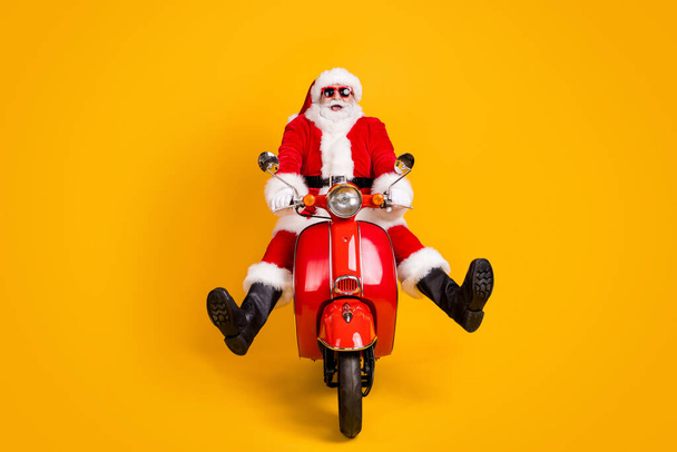 Portrait of his he nice funny playful childish comic hilarious cheerful Santa riding moped having fun fooling fast speed isolated bright vivid shine vibrant yellow color background - Foto, afbeelding
