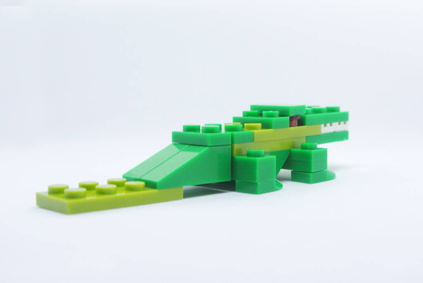 Kształt zielonego krokodyla jest wykonany z kolorowych plastikowych klocków zabawkowych. - Zdjęcie, obraz