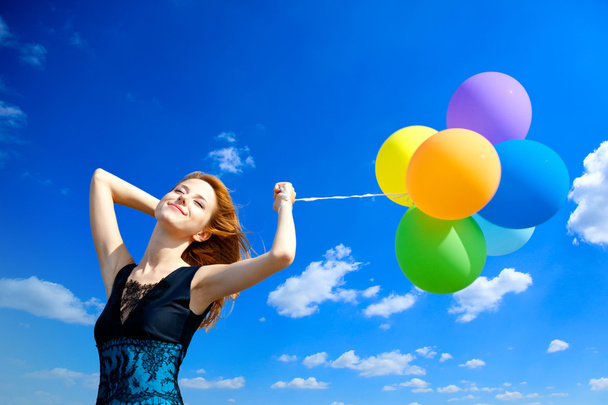 Redhead girl with colour balloons at blue sky background. - Foto, Imagen
