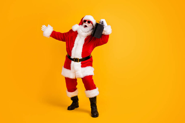 Full length body size view of his he nice funny cheerful cheery white-haired Santa dj mc deejay carrying boombox dancing having fun isolated bright vivid shine vibrant yellow color background - Foto, afbeelding