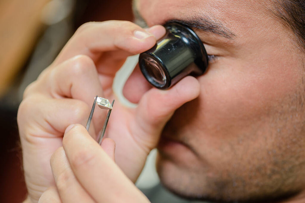 Closeup of jeweler inspecting gemstone - 写真・画像