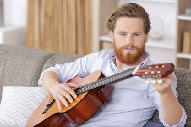 male musician tuning an acoustic guitar - Foto, Bild