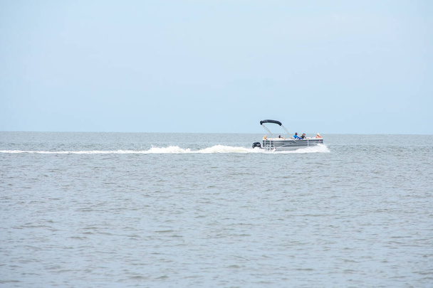 Μια βάρκα που τρέχει στον ωκεανό σε μια συννεφιασμένη μέρα - Φωτογραφία, εικόνα