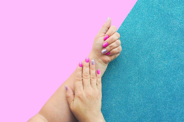 mains féminines avec belle manucure lilas sur fond rose et bleu brillant - Photo, image