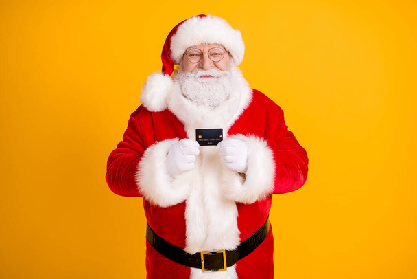 Photo of jolly holly fairy santa claus hold credit card recommend bank earnings money savings for x-mas christmas buyer gift present wear cap headwear isolated bright shine color background - 写真・画像
