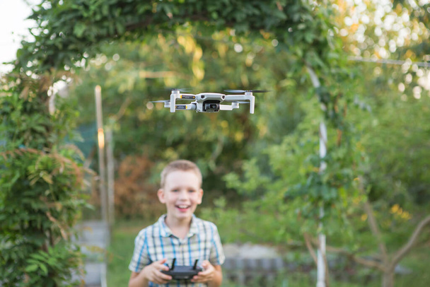 Gyerek repülő drón. A fiú drónokat irányít. Gyermekműveleti Négyes helikopter. Drón távirányítót használó kis pilóta - Fotó, kép