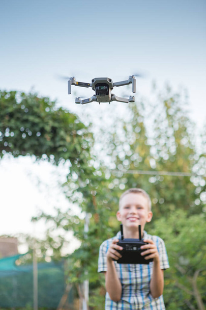 Kid flying drone. Boy operate drones. Child Operating Quadcopter. Little Pilot Using Drone Remote Controller - Fotó, kép