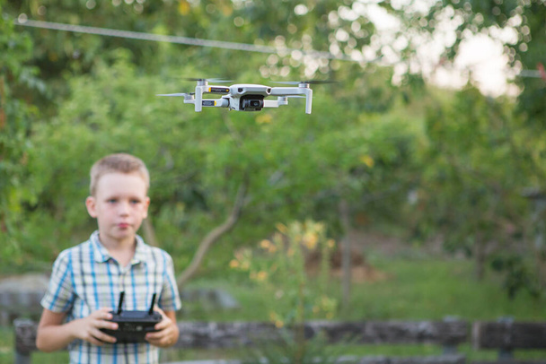 Dzieciak latający dronem. Chłopak operuje dronami. Dziecięcy kwadrans operacyjny. Mały pilot za pomocą zdalnego sterowania dronem - Zdjęcie, obraz