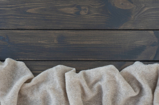 beige warm wool plaid lie on dark wooden background. Copy space for text or for inscription.  - Fotografie, Obrázek