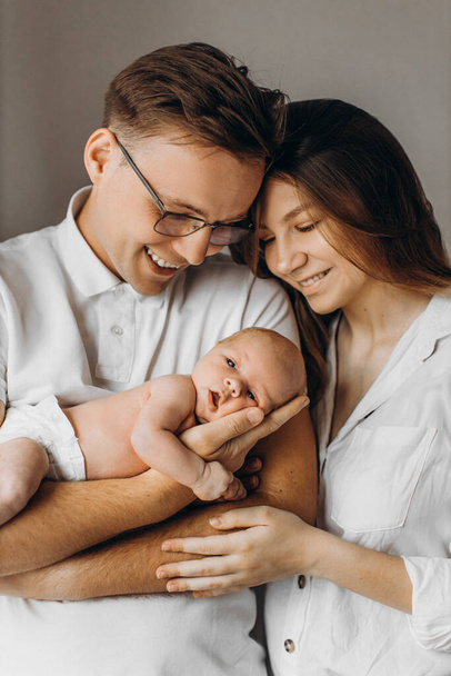 Caring parents with newborn baby, loving dad gently hold little daughter in arms, beautiful mother hug strong father, smiling, enjoy happy moments, young family concept - Foto, imagen