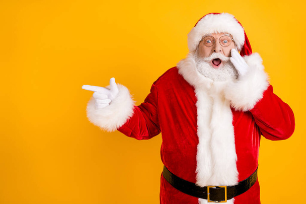 Photo astonished fat santa claus point finger impressed x-mas newyear christmas magic miracle ads promo touch white gloves face scream wear headwear isolated bright shine color background - Photo, image