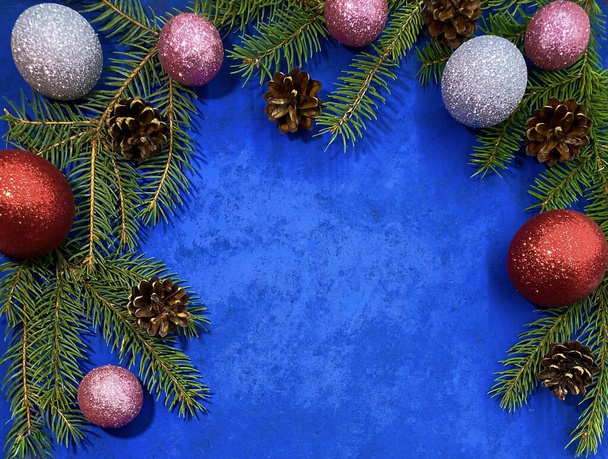 Fondo brillante de Navidad. Ramas de abeto con conos de pino y bolas sobre una superficie azul abstracta. Vista desde la parte superior, copiar espacio. - Foto, imagen