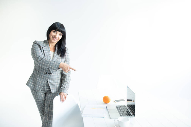 Bizneswoman wskazuje palcem na biurko z laptopem. Biznes online, kariera, koncepcja lekcji online. Odbiór. Białe tło.  - Zdjęcie, obraz