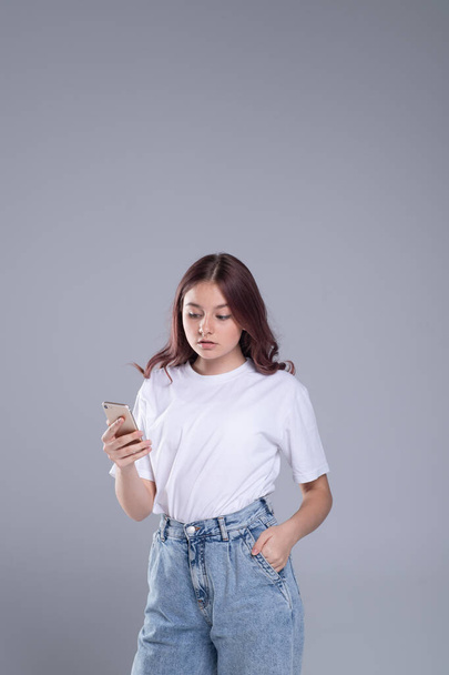 Generation Z lifestyle. Cute girl teenager with mobile phone. Emotional, surprised face. The concept of chat, news in a mobile phone.  - Photo, Image