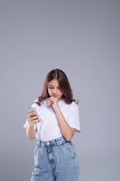 Generation Z lifestyle. Cute girl teenager with mobile phone. Emotional, surprised face. The concept of chat, news in a mobile phone.  - Fotó, kép