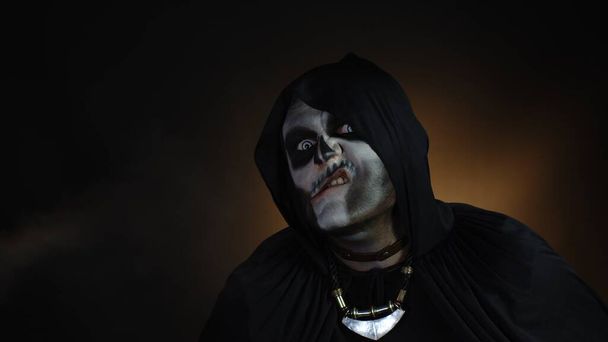 Homem sinistro com maquiagem esqueleto de Halloween fazendo rostos, olhando para a câmera, tentando assustar - Foto, Imagem
