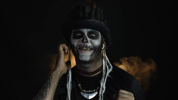 Gruseliger Typ im Kostüm von Halloween-Skelett mit Kopfhörern, Musik hören, tanzen, feiern - Foto, Bild