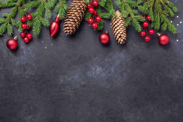 Christmas background with fir tree, holly and red balls on dark stone background. Top view Copy space - Image - Photo, image