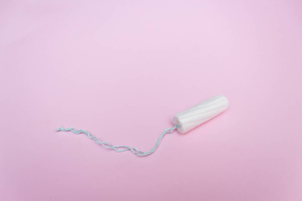 Menstrual tampon on a pink background. Menstruation time. Hygiene and protection. - Фото, изображение