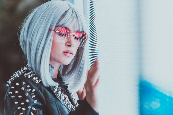 Image of a beautiful young woman posing against a led panel. teenager with alternative look and grey wig making urban portraits - Photo, Image