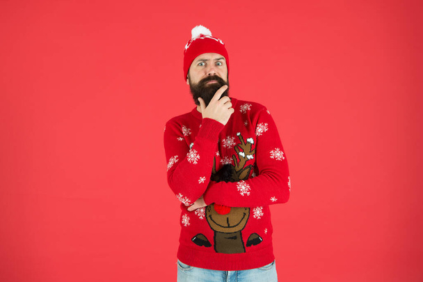 Consequence. What to do. Need inspiration. New year concept. Join winter holiday party. Christmas Party. Winter outfit. Hipster emotional bearded man wear winter sweater and hat red background - Φωτογραφία, εικόνα