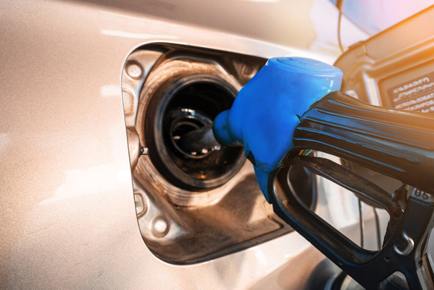 Het blauwe tankpistool wordt in het gat van de benzinetank van de auto geplaatst bij tanken met benzine. Close-up van het brandstofpistool. - Foto, afbeelding