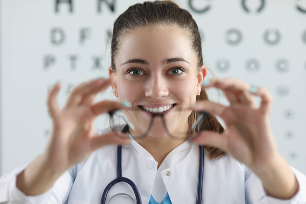 Mujer oftalmóloga da gafas para montar sobre fondo de mesa para medir la visión - Foto, imagen