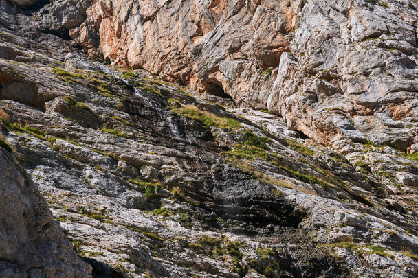 дно почти сухой водопад на крутой скале в горах с тонким ручьем текучей воды - Фото, изображение