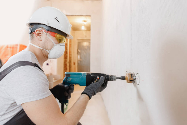 İnşaatçı işçi pnömatik çekiç delme delikleri beton tuğla duvar ve elektrik kablosu için elmas taç, soket, anahtar - Fotoğraf, Görsel