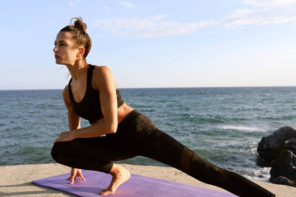 Head shot of woman, doing yoga asana in the beach with eyes closed, wearing sport clothes with defocused background. - 写真・画像