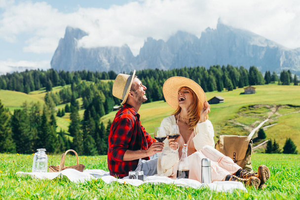 Happy couple on vacation on the italian dolomites mountains. Young man and woman making activities on a beautiful green meadow - Photo, image