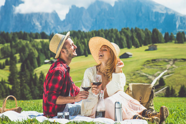 Happy couple on vacation on the italian dolomites mountains. Young man and woman making activities on a beautiful green meadow - Foto, Bild