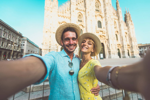 Image of a happy couple on vacation. Young man and woman taking a selfie in Milan near the Duomo cathedral - Foto, Imagen