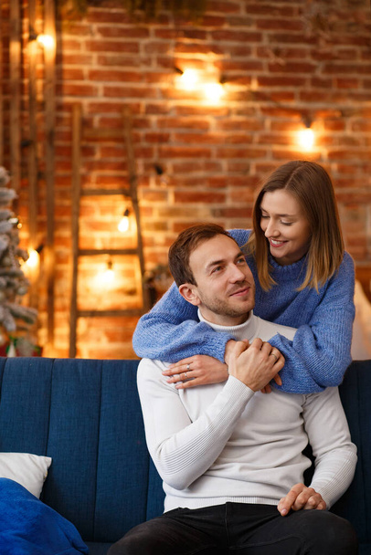 Portrait of beautiful smiling couple hugging at Christmas eve. Beautiful young couple at home enjoying spending time together. Winter holidays, Christmas celebrations, New Year concept - Photo, image