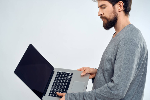 Ein Mann im grauen Pullover mit Laptop reicht Lifestyletechnologie Kommunikation Internet-Arbeit - Foto, Bild
