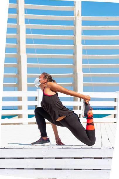 Mujer joven con mascarilla quirúrgica protectora realizando ejercicios de estiramiento de yoga al aire libre durante la pandemia de coronavirus covid-19 - Foto, imagen