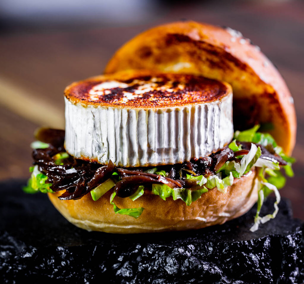 verse hamburger met geitenkaas close-up gefotografeerd op rustieke dienblad - Foto, afbeelding