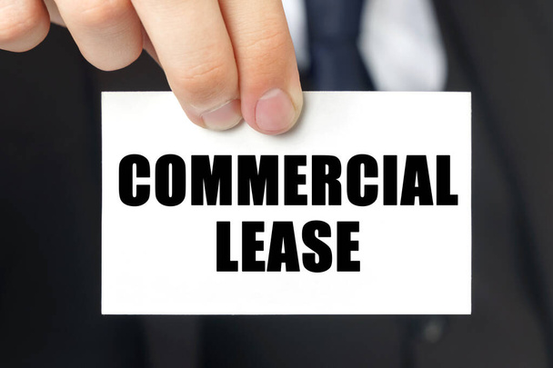 Business concept. Businessman shows a card with the text - COMMERCIAL LEASE - Photo, image
