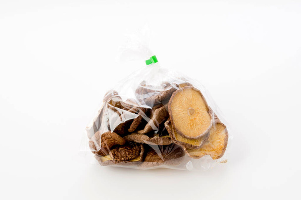 funghi shitake secchi in sacchetto di plastica su sfondo bianco - Foto, immagini