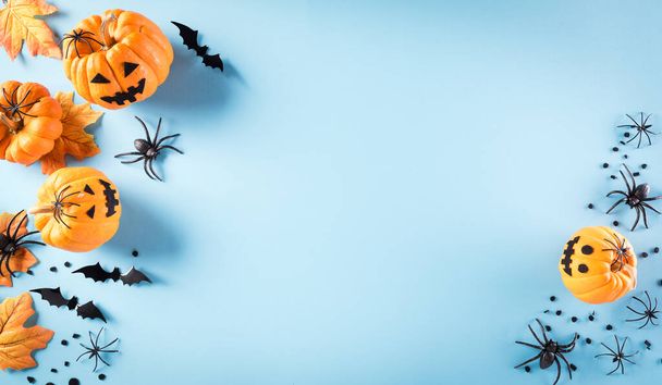 Decorações de Halloween feitas de abóbora, morcegos de papel e aranha preta no fundo azul pastel. Flat lay, vista superior com espaço de cópia para texto. - Foto, Imagem