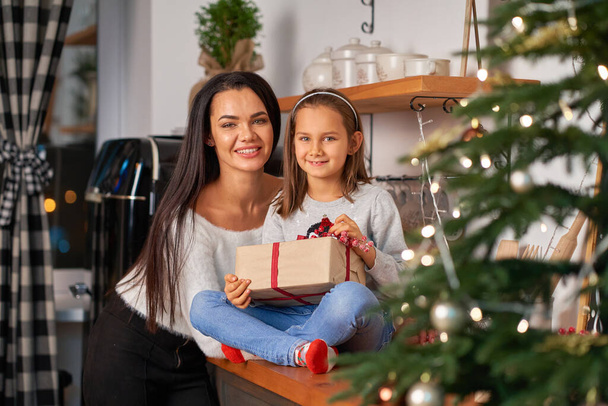 Happy mom with little daughter who received a Christmas present from Santa. - Zdjęcie, obraz