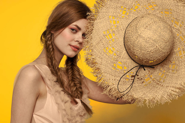 Sarı arkaplan duygularıyla elinde hasır şapkalı bir kadın...  - Fotoğraf, Görsel