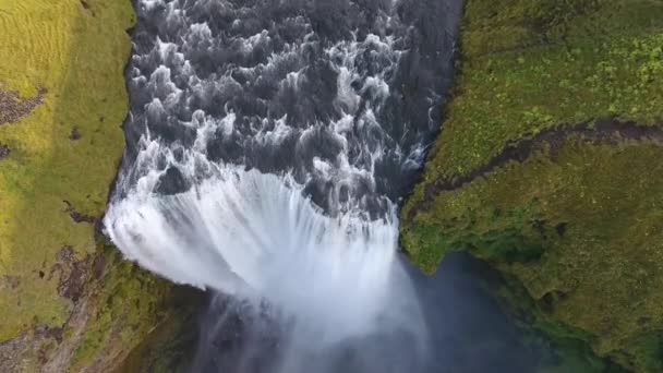 Aereo drone colpo che vola sopra la famosa cascata Skogafoss in Islanda. Giorno soleggiato volo di media altitudine - Filmati, video