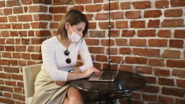 Fiatal üzletasszony védő maszk dolgozik notebook kávézóban - Felvétel, videó