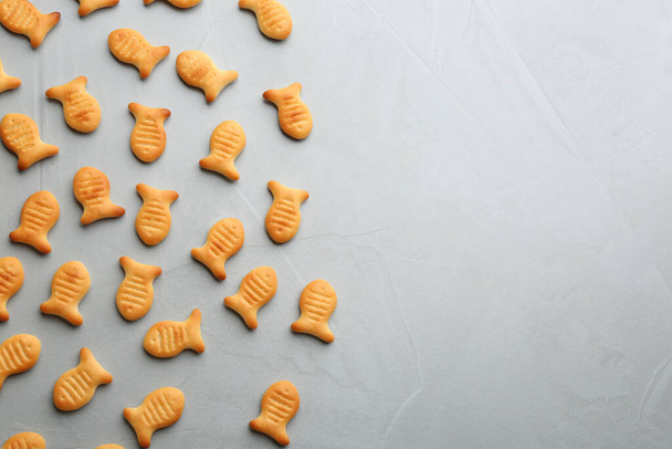Delicious goldfish crackers on grey table, flat lay. Space for text - Photo, image