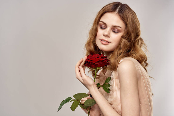 pretty woman with red flower on beige background portrait holidays - Photo, image